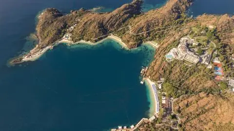 Aerial view of a bay with sandy beaches, piers and a hotel complex on the hillside