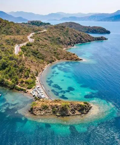 Turquoise bay with rocky coastline and a small peninsula extending into calm sea