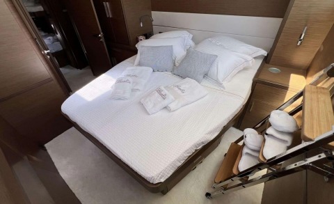 Atlantis yacht with a double bed, white bedding and pillows, bedside cabinets, and stairs beside the cabin
