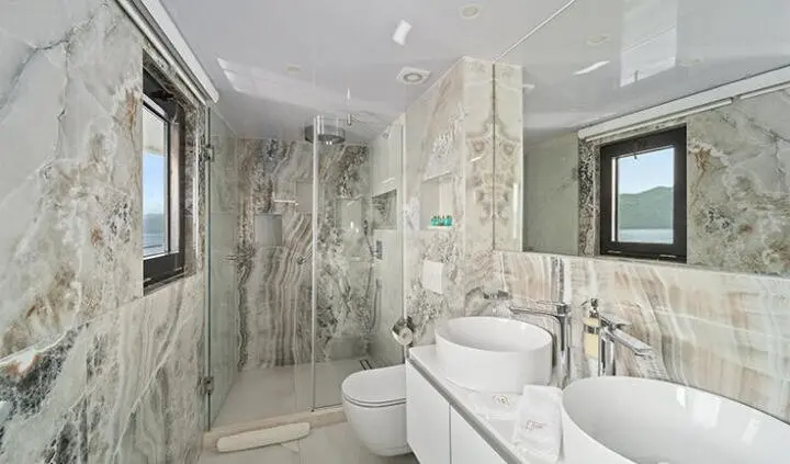 Luxurious master cabin with marble walls, bed, and ensuite bathroom fixtures