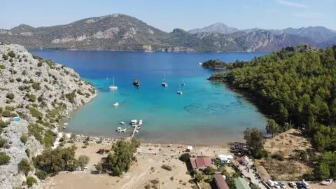 Turquoise bay with sailboats near a rocky jetty and clear water