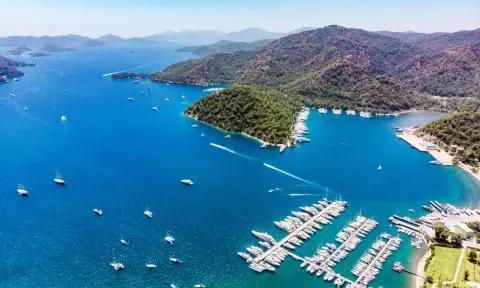 Aerial view of a marina with numerous yachts docked along piers beside blue bay waters