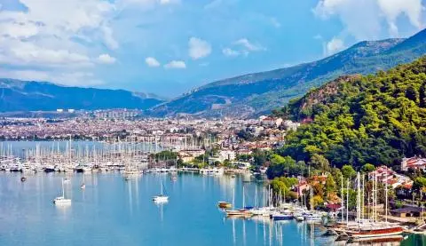 Yacht marina with sailboats, calm water and a forested hillside town