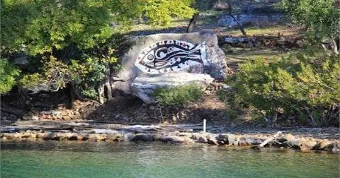 Rock shoreline with a circular mural featuring a fish design near the water