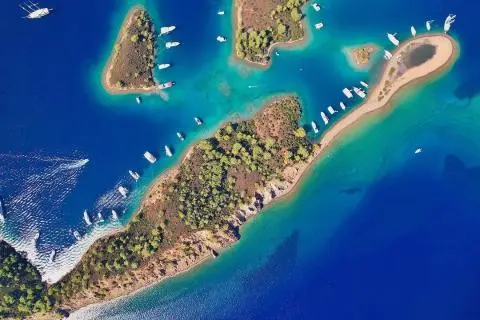 Aerial view of anchored yachts near wooded islets with turquoise water