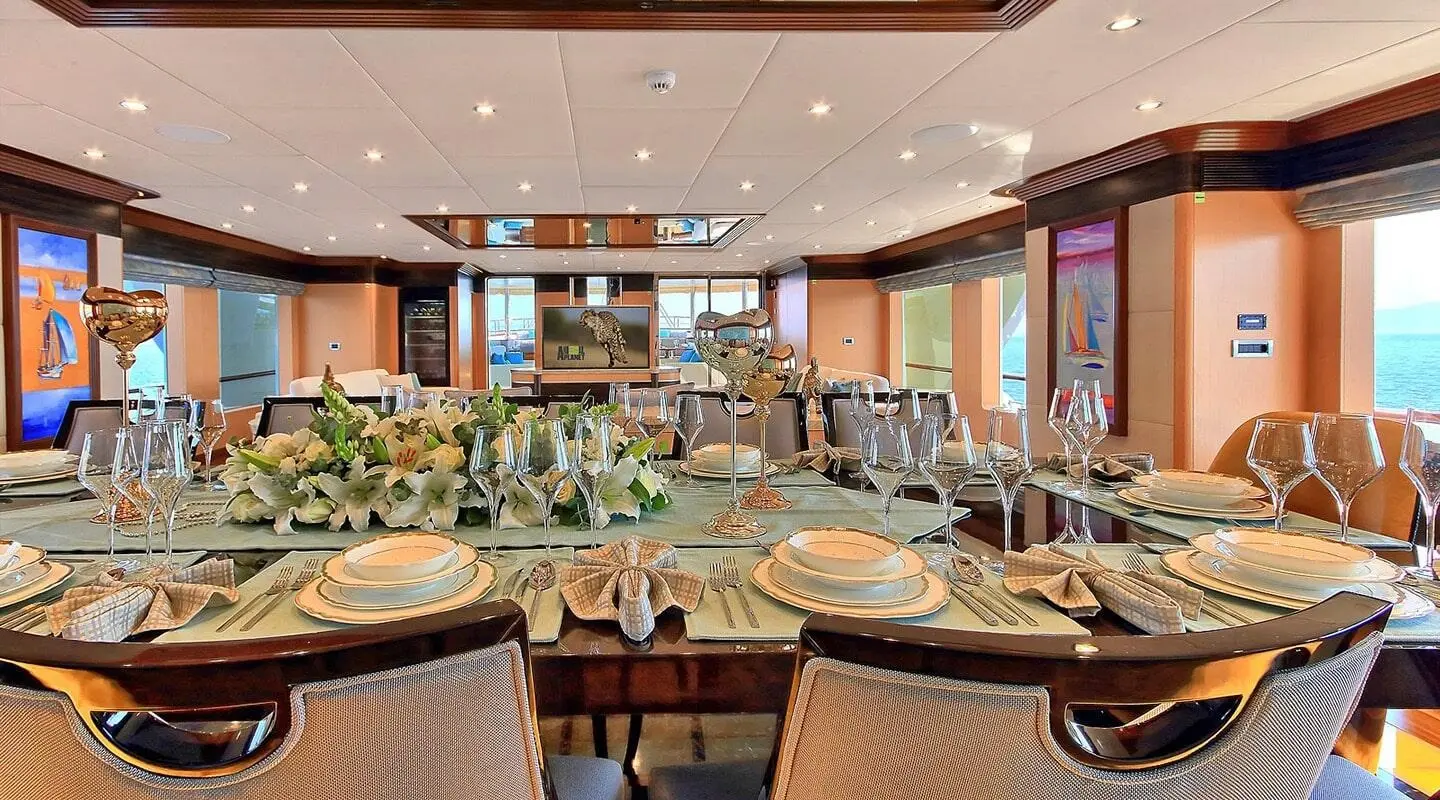 Meira yacht dining salon set for a formal meal with a centerpiece of white florals