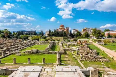View of ancient ruins with domed church and blue sky over green lawns