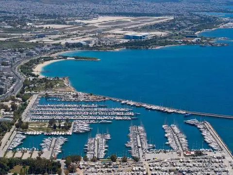 Aerial view of a coastal marina with numerous yachts docked along piers