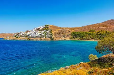 Rocky headland with white houses above clear turquoise sea on a sunny coastline