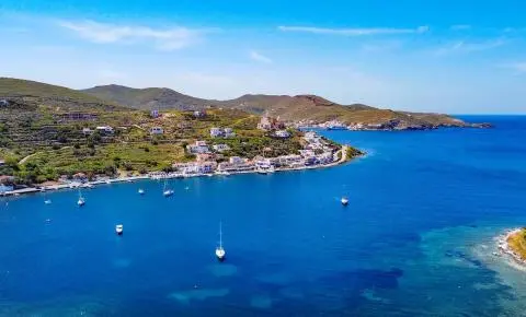 Coastal village with sailboats in a calm blue bay and hillside homes