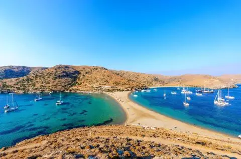 Narrow sandy tombolo between two turquoise bays with multiple anchored sailing yachts