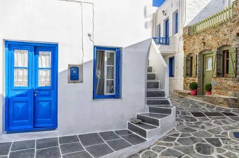 White house with blue door and curved stone steps along a narrow cobblestone alley