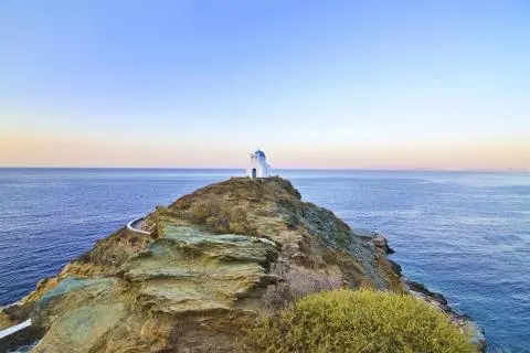 Rocky coastal promontory with a small lighthouse-like beacon overlooking calm sea