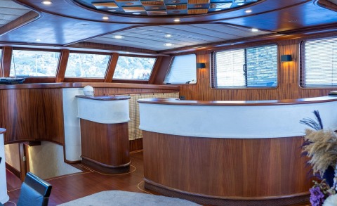 Luxurious yacht interior with wooden panels and white bar counter, windows with outside view