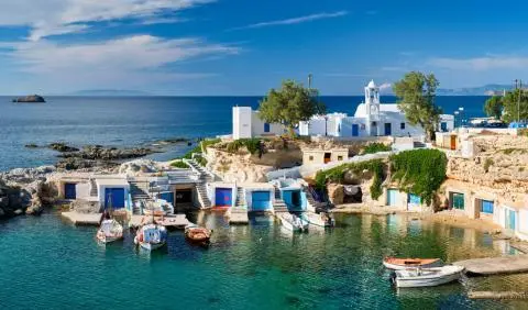 Turquoise water with small boats near white houses along a rocky coastline