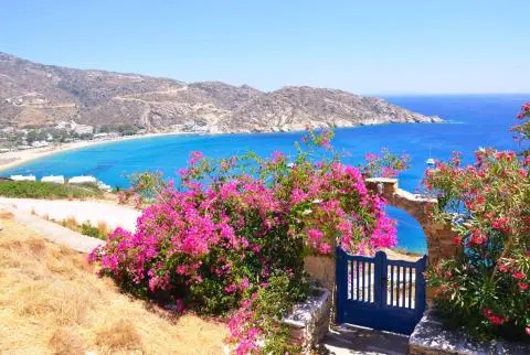 Stone archway with blue gate and bougainvillea overlooking turquoise sea