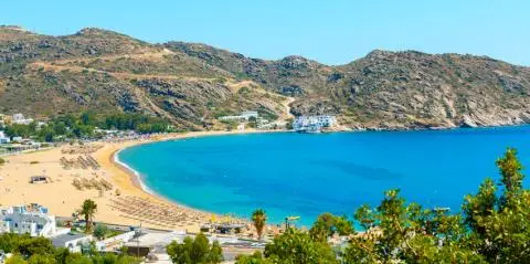 Turquoise bay with sandy beach and rows of umbrellas under blue sky