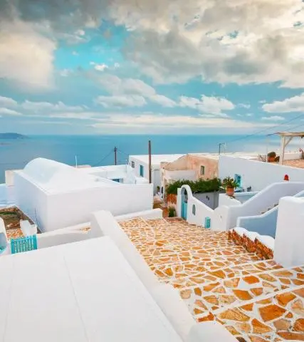 Whitewashed houses and stone-paved steps leading down toward the Aegean Sea, blue doors