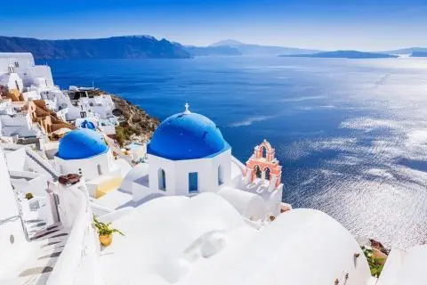 White houses and blue-domed churches on a cliff overlooking the Aegean Sea, Santorini