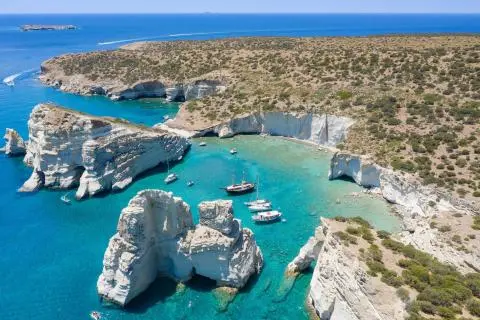 Aerial view of a small cove with white limestone rocks and several boats on turquoise water