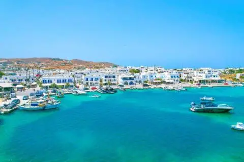 Turquoise sea with boats moored at a quay in front of whitewashed seaside houses