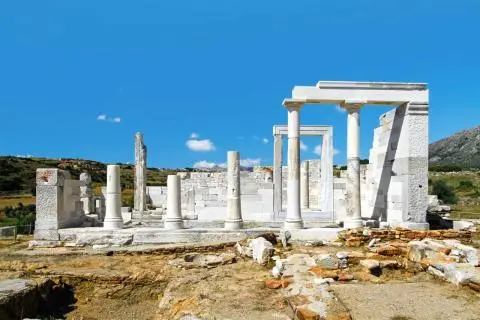 Open-air ancient ruins with white marble columns and partial walls under a clear blue sky