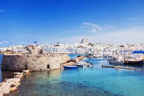 Calm harbor with stone quay, small boats and white houses under a clear blue sky