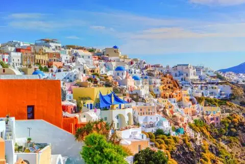 Cliffside Mediterranean village with whitewashed houses, blue-domed churches and colorful buildings
