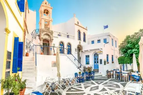 White-stoned square with blue-doored buildings, stairs and rows of outdoor chairs