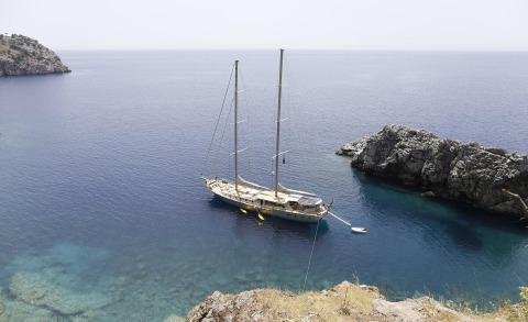 Silver Moon sailboat anchored near rocky coastline in turquoise waters