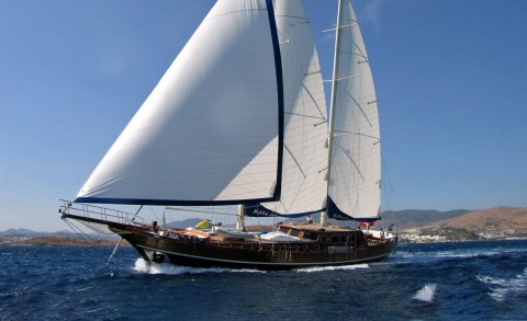 Sailing yacht with two large sails on the open sea, hull and deck visible