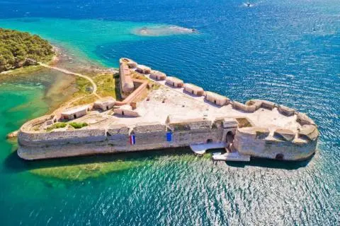 Aerial view of a small island fortress with stone ramparts surrounded by blue sea
