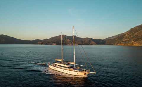 Queen Of Makri sailing along a calm sea with rugged coastline in the background