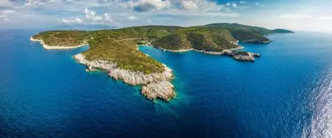 Aerial view of rocky headlands and small coves with green vegetation surrounded by deep blue sea