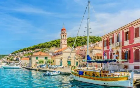 Wooden sailing yacht moored at quay with waterfront town and church tower