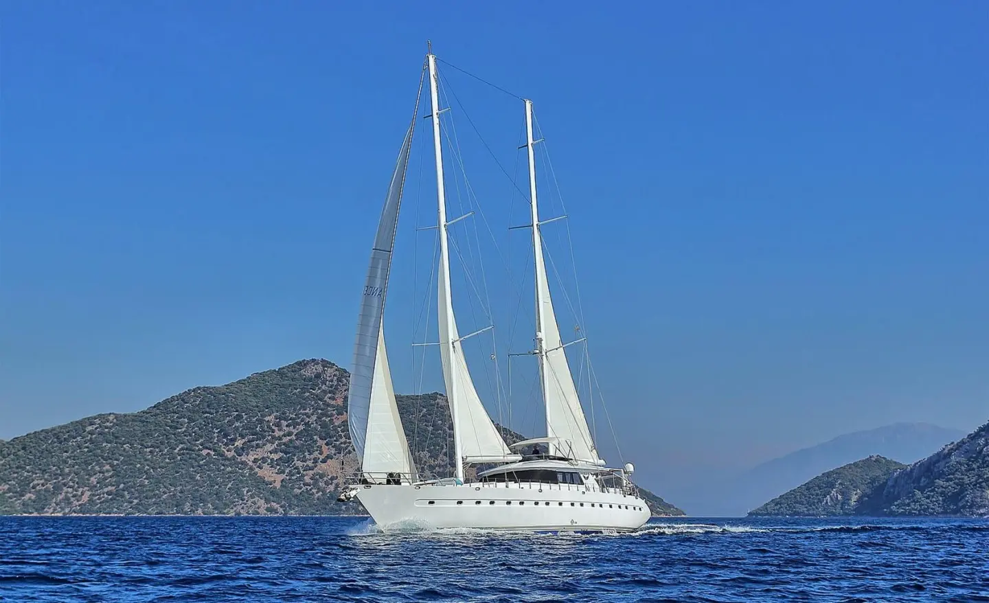 Angelo II luxury gulet sailing at sunset with white sails on blue sea