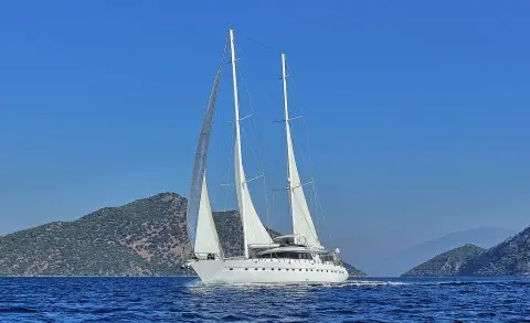 Angelo II luxury gulet sailing at sunset with white sails on blue sea