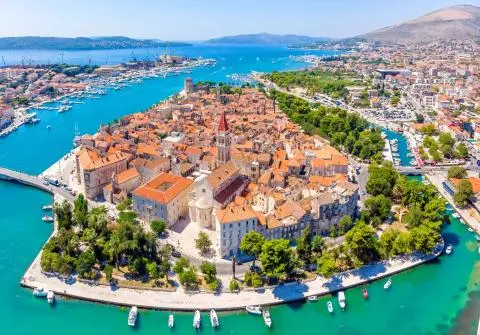 Aerial view of Trogir peninsula with red-tiled roofs, stone buildings and turquoise harbor waters