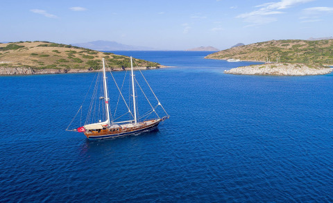 Zephyria II, classic 34.5m sailing yacht anchored in blue Mediterranean waters near rocky islands