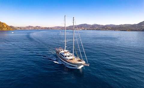 Double Eagle sailing yacht on calm blue sea with distant coastline and hills