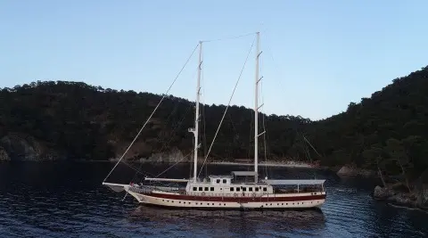 Gulet Tersane 8 anchored near hillside, two masts, dark hull, calm sea