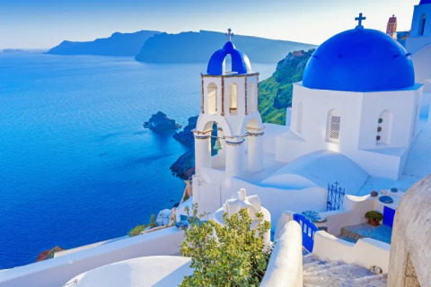 Santorini coastal view with white buildings and blue-domed church overlooking the Aegean Sea