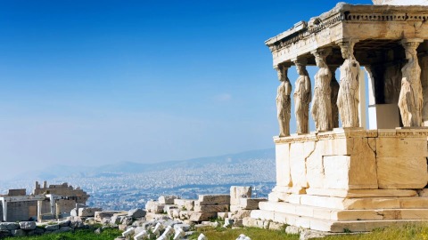Caryatid statues on the Acropolis porch with Athens cityscape and clear blue sky