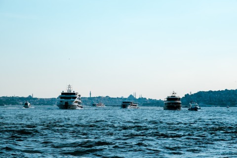 Several motor yachts and tour boats sailing on open water with Istanbul skyline in background