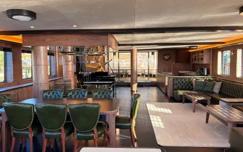 Luxurious interior with a large wooden dining table and green leather chairs in a lounge