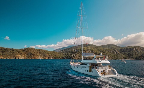 Belgin Sultan luxury 35m yacht cruising along blue waters near a forested coastline