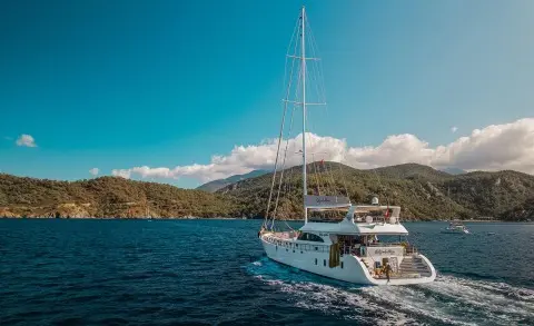 Belgin Sultan luxury 35m yacht cruising along blue waters near a forested coastline
