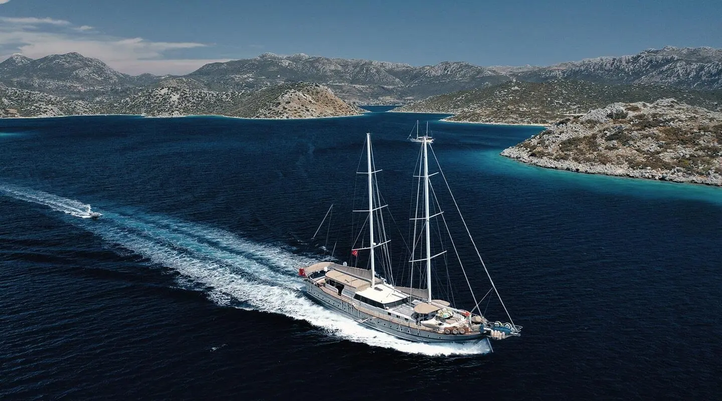 Nevra Queen luxury gulet sailing at sunset with coastal cliffs in view