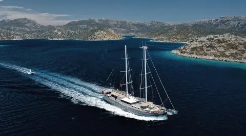 Nevra Queen luxury gulet sailing at sunset with coastal cliffs in view