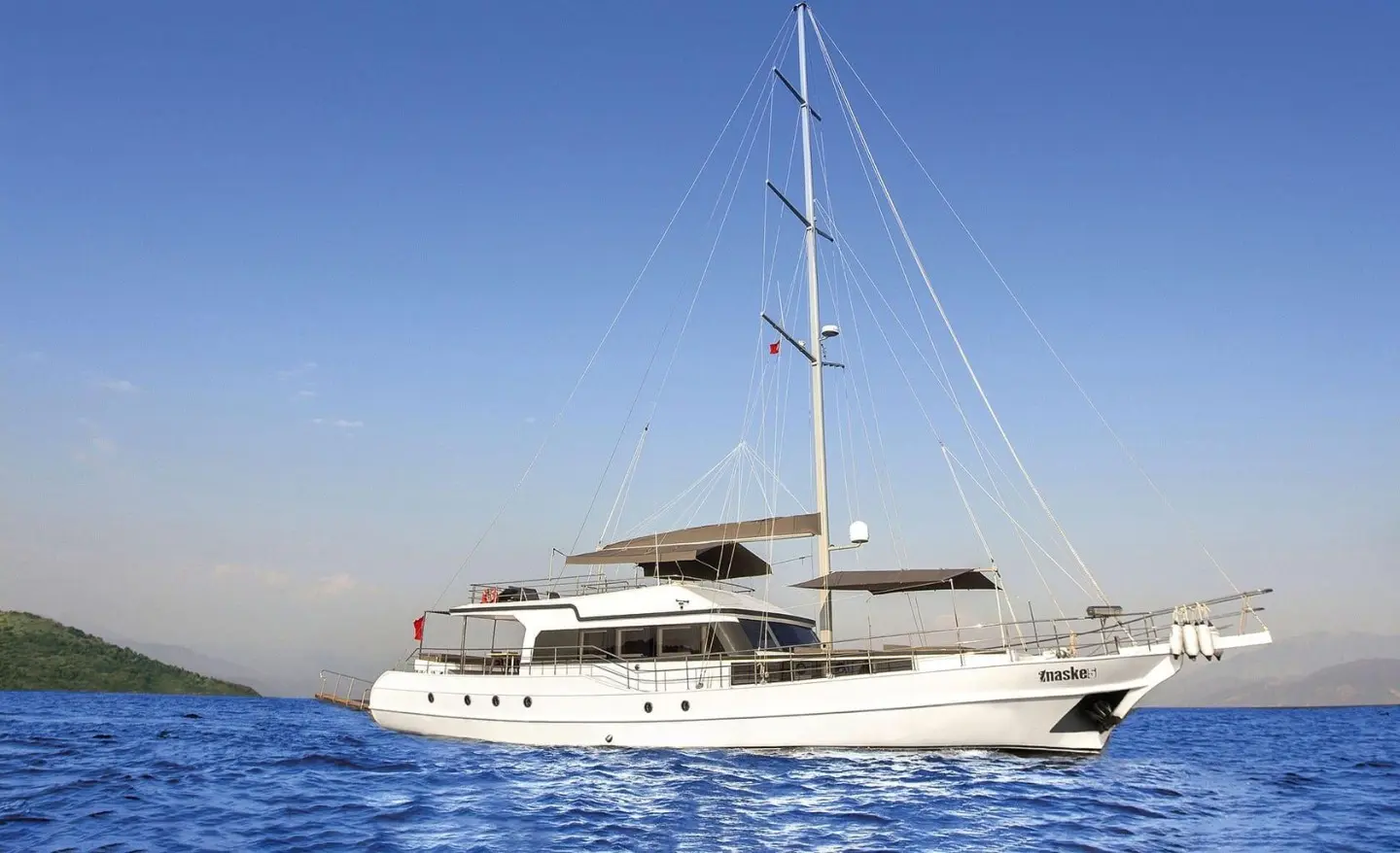 Maske 5 yacht anchored on blue sea at sunset with sails and a deck